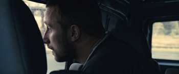 Movie still from “Rust and Bone” (2012), directed by Jacques Audiard – A person wearing a suit driving a car; Close Up shot, Low angle