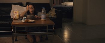 Movie still from “Rust and Bone” (2012), directed by Jacques Audiard – A woman sitting at a table with a bottle of milk; Wide shot, High angle
