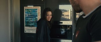 Movie still from “Rust and Bone” (2012), directed by Jacques Audiard – A woman standing in front of an oven in a kitchen; Medium shot, Over the shoulder angle