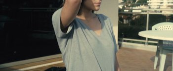 Movie still from “Rust and Bone” (2012), directed by Jacques Audiard – A woman in a gray shirt is holding her hand up to her head; Close Up shot, High angle
