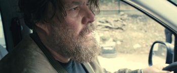 Movie still from “Rust and Bone” (2012), directed by Jacques Audiard – A man with a long beard looking out of a car window; Close Up shot, Over the shoulder angle