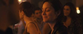 Movie still from “Rust and Bone” (2012), directed by Jacques Audiard – A person smiling at a party; Close Up shot, Over the shoulder angle