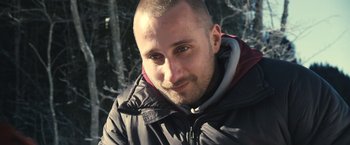 Movie still from “Rust and Bone” (2012), directed by Jacques Audiard – A person wearing a jacket near a forest; Close Up shot, High angle
