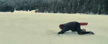 Movie still from “Rust and Bone” (2012), directed by Jacques Audiard – A man is laying in the snow on the ground; Wide shot, High angle