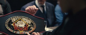 Movie still from “Rust and Bone” (2012), directed by Jacques Audiard – Two men are sitting at a table and one of them is holding a bag; Extreme Close Up shot, Over the shoulder angle