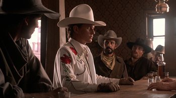 Movie still from “Rustlers' Rhapsody” (1985), directed by Hugh Wilson – A group of men sitting at a table wearing cowboy hats; Medium shot, Over the shoulder angle