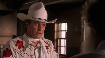 Movie still from “Rustlers' Rhapsody” (1985), directed by Hugh Wilson – A man wearing a white cowboy hat in a room; Close Up shot, Over the shoulder angle
