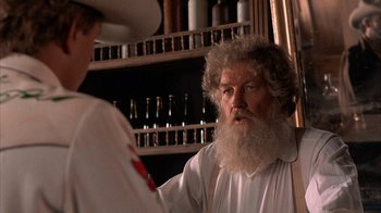 Movie still from “Rustlers' Rhapsody” (1985), directed by Hugh Wilson – An old man with a long white beard is looking at a woman; Close Up shot, Over the shoulder angle