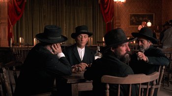 Movie still from “Rustlers' Rhapsody” (1985), directed by Hugh Wilson – A group of men sitting around a table; Medium shot, Low angle