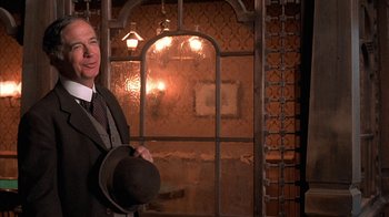 Movie still from “Rustlers' Rhapsody” (1985), directed by Hugh Wilson – A man in a suit and hat standing in front of a window; Close Up shot, Over the shoulder angle