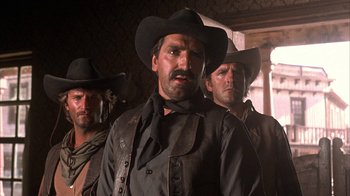 Movie still from “Rustlers' Rhapsody” (1985), directed by Hugh Wilson – A group of men standing next to each other in a room; Close Up shot, Low angle
