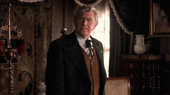 Movie still from “Rustlers' Rhapsody” (1985), directed by Hugh Wilson – An older man wearing a suit and tie in front of a window; Medium shot, Low angle