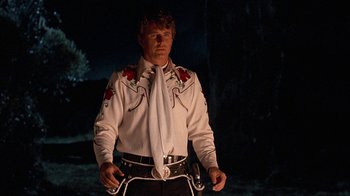 Movie still from “Rustlers' Rhapsody” (1985), directed by Hugh Wilson – A man wearing a white shirt and a white tie; Medium shot, Low angle