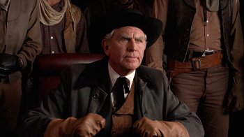 Movie still from “Rustlers' Rhapsody” (1985), directed by Hugh Wilson – An older man wearing a black hat and a black jacket; Close Up shot, Over the shoulder angle
