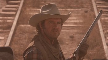 Movie still from “Rustlers' Rhapsody” (1985), directed by Hugh Wilson – A man in a cowboy hat holding a gun; Close Up shot, Low angle