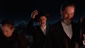 Movie still from “Rustlers' Rhapsody” (1985), directed by Hugh Wilson – A man with a beard and a hat is waving; Medium shot, Low angle