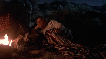 Movie still from “Rustlers' Rhapsody” (1985), directed by Hugh Wilson – A man laying on the ground in the dark; Medium shot, High angle