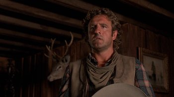 Movie still from “Rustlers' Rhapsody” (1985), directed by Hugh Wilson – A man standing next to a deer in a room; Close Up shot, Low angle