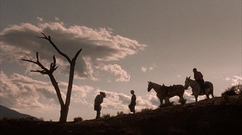 Movie still from “Rustlers' Rhapsody” (1985), directed by Hugh Wilson – Two men and a horse on a hill under a cloudy sky; Extreme Wide shot, Low angle