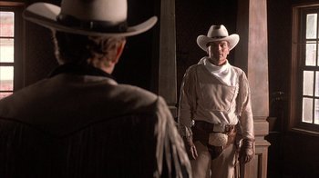 Movie still from “Rustlers' Rhapsody” (1985), directed by Hugh Wilson – A man wearing a cowboy hat and a white cowboy hat; Medium shot, Over the shoulder angle