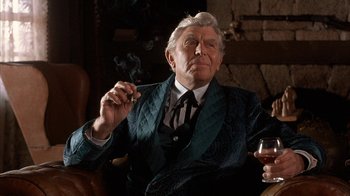 Movie still from “Rustlers' Rhapsody” (1985), directed by Hugh Wilson – An older man smoking a cigarette while holding a glass of wine; Medium shot, Over the shoulder angle