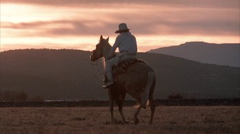 Movie still from “Rustlers' Rhapsody” (1985), directed by Hugh Wilson – A man riding on the back of a brown horse; Wide shot, Low angle