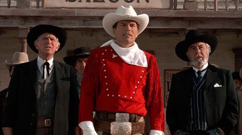 Movie still from “Rustlers' Rhapsody” (1985), directed by Hugh Wilson – A man in a red shirt and white cowboy hat; Medium shot, Low angle