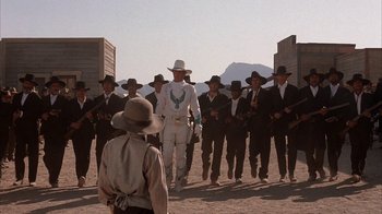 Movie still from “Rustlers' Rhapsody” (1985), directed by Hugh Wilson – A group of men in suits and hats standing next to each other in the desert; Wide shot, Low angle