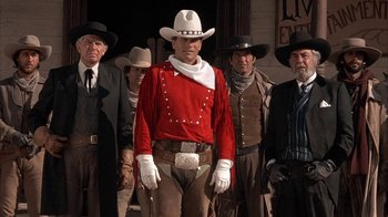 Movie still from “Rustlers' Rhapsody” (1985), directed by Hugh Wilson – A group of men standing next to each other wearing cowboy hats; Medium shot, Low angle
