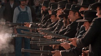 Movie still from “Rustlers' Rhapsody” (1985), directed by Hugh Wilson – A group of men in black suits and black hats holding guns; Wide shot, Low angle