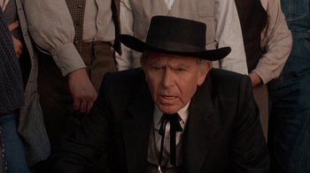 Movie still from “Rustlers' Rhapsody” (1985), directed by Hugh Wilson – An older man wearing a black suit and a black hat; Close Up shot, Over the shoulder angle