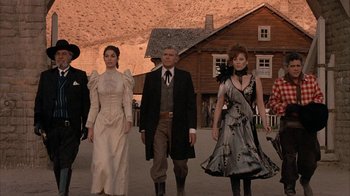 Movie still from “Rustlers' Rhapsody” (1985), directed by Hugh Wilson – A group of people walking on a dirt road; Wide shot, Low angle