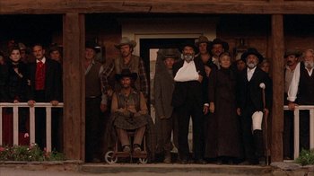 Movie still from “Rustlers' Rhapsody” (1985), directed by Hugh Wilson – A group of men and women standing in front of a building; Wide shot, Low angle