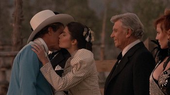 Movie still from “Rustlers' Rhapsody” (1985), directed by Hugh Wilson – A man and a woman kissing in front of a man and a woman; Medium shot, Over the shoulder angle
