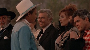 Movie still from “Rustlers' Rhapsody” (1985), directed by Hugh Wilson – A man and two women standing next to each other; Medium shot, Over the shoulder angle