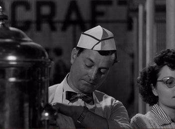 Movie still from “Saboteur” (1942), directed by Alfred Hitchcock – A man wearing a paper hat and a bow tie; Medium shot, Low angle