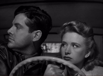 Movie still from “Saboteur” (1942), directed by Alfred Hitchcock – A man and a woman sitting in the drivers seat of a car; Close Up shot, Low angle