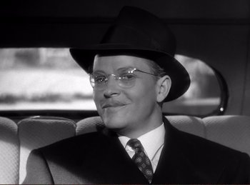 Movie still from “Saboteur” (1942), directed by Alfred Hitchcock – A black and white photo of a man wearing a hat and glasses; Close Up shot, Low angle