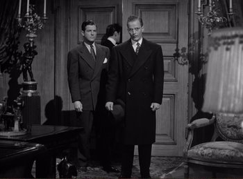 Movie still from “Saboteur” (1942), directed by Alfred Hitchcock – Two men standing in front of a door way; Medium shot, Low angle