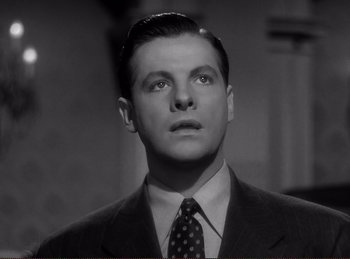 Movie still from “Saboteur” (1942), directed by Alfred Hitchcock – A black and white photo of a man in a suit and tie; Close Up shot, Low angle