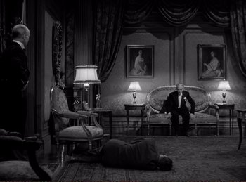 Movie still from “Saboteur” (1942), directed by Alfred Hitchcock – A man and a woman sitting on the floor of a living room; Wide shot, High angle