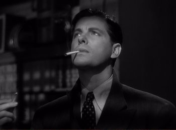 Movie still from “Saboteur” (1942), directed by Alfred Hitchcock – A black and white photo of a man smoking a cigarette; Close Up shot, Low angle