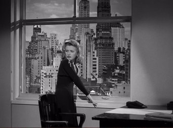 Movie still from “Saboteur” (1942), directed by Alfred Hitchcock – A black and white photo of a woman standing in front of a window; Medium shot, Low angle