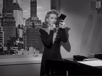 Movie still from “Saboteur” (1942), directed by Alfred Hitchcock – A black and white photo of a woman taking a picture of herself; Medium shot, Over the shoulder angle
