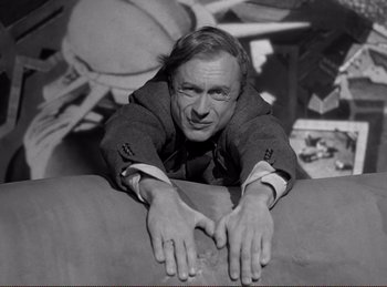 Movie still from “Saboteur” (1942), directed by Alfred Hitchcock – A black and white photo of a man sitting on a couch; Medium shot, Overhead angle