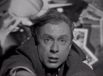 Movie still from “Saboteur” (1942), directed by Alfred Hitchcock – An old black and white photo of a man looking at the camera; Close Up shot, High angle