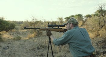 Movie still from “Safari” (2016), directed by Ulrich Seidl – A man is holding a rifle and aiming at a target; Medium shot, Over the shoulder angle