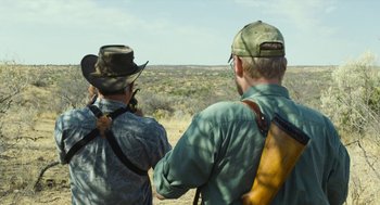 Movie still from “Safari” (2016), directed by Ulrich Seidl – Two men looking out over a desert plain; Medium shot, Over the shoulder angle
