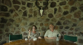 Movie still from “Safari” (2016), directed by Ulrich Seidl – A man and a woman sitting at a wooden table; Medium shot, High angle