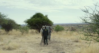 Movie still from “Safari” (2016), directed by Ulrich Seidl – A group of people walking on a dirt road; Wide shot, Low angle